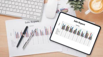 Tablet with charts and reports on office desk workplace. Top view flat lay photo