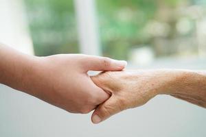 Asian young boy holding old grandmother woman hand together with love and care. photo