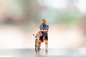 Miniature cyclist standing with bike, World bicycle day concept photo