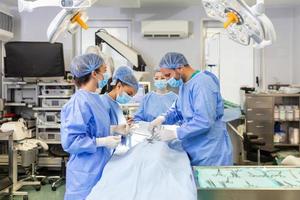 Concentrated Surgical team operating a patient in an operation theater. Well-trained anesthesiologist with years of training with complex machines follows the patient throughout the surgery. photo