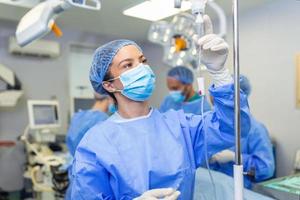 Female Doctor in the operating room putting drugs through an IV - surgery concepts photo
