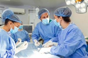 Diverse Team of Professional surgeon, Assistants and Nurses Performing Invasive Surgery on a Patient in the Hospital Operating Room. Surgeons Talk and Use Instruments. Real Modern Hospital. photo