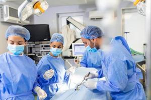 Medical team of surgeons in hospital doing minimal invasive surgical interventions. Surgery operating room with electrocautery equipment for cardiovascular emergency surgery center. photo