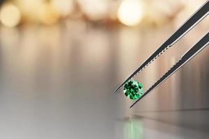 Green emerald crystal diamond and tweezers on a glossy background with objects soft focusing 3d rendering photo