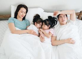 joven asiático familia en cama foto