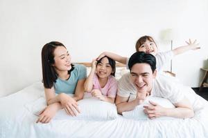 joven asiático familia en cama foto