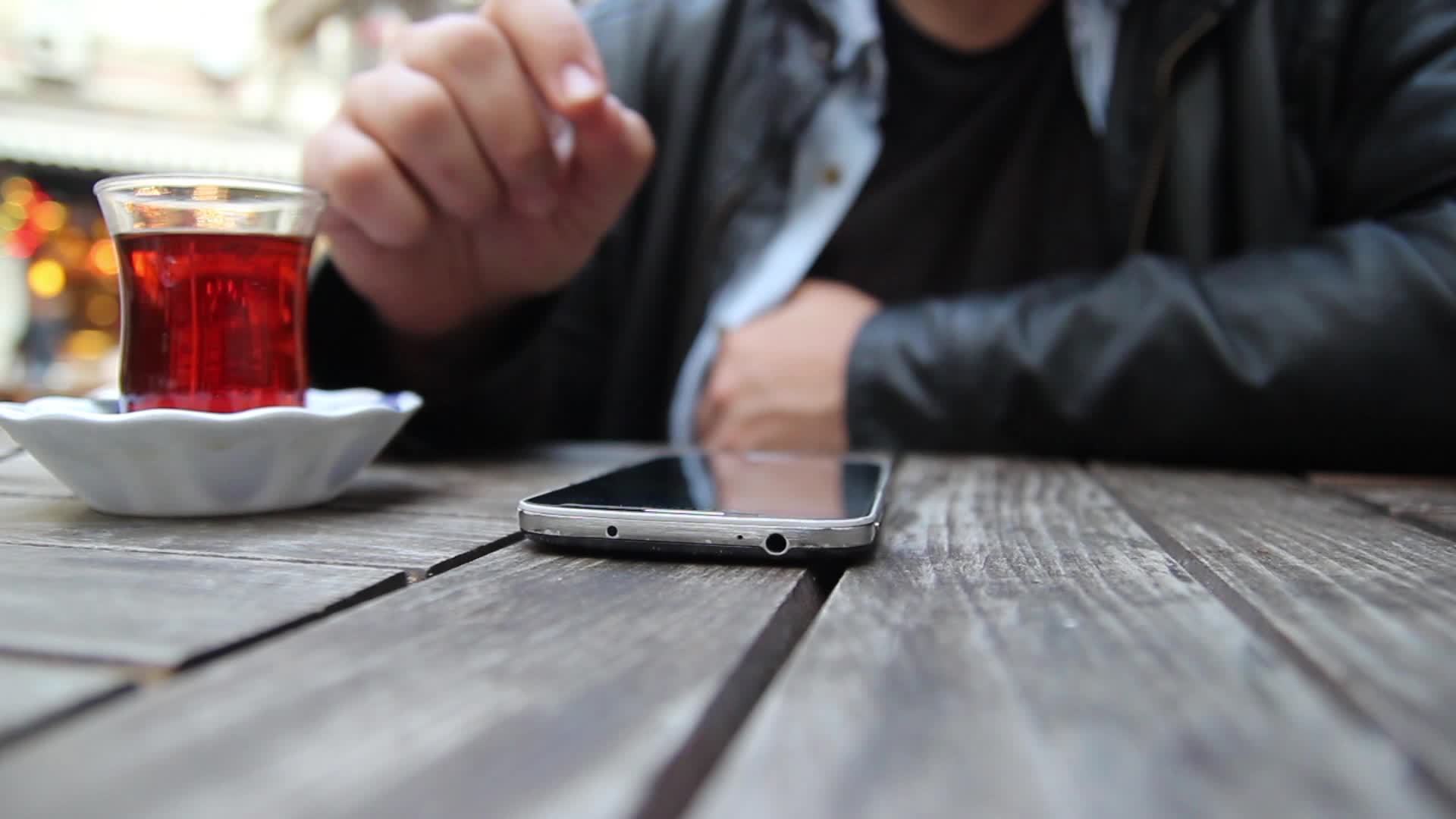 Man use smartphone and drink tea, turkish tea, in a cafe, selective