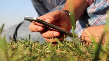 Man use smartphone with a view, sit and lay on the lawn, selective focus, noise effect video