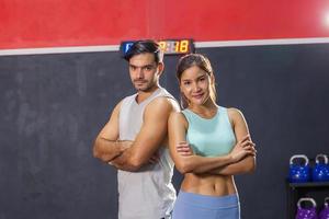 deportivo Pareja amigos en pie brazos cruzado, joven hombre y mujer relajante en Deportes trajes a el gimnasia, deporte y aptitud conceptos foto