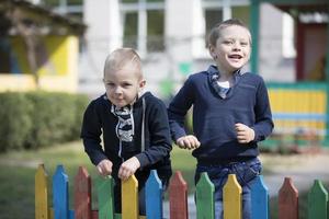 dos pequeño amigos son jugando. jardín de infancia Niños en el patio de recreo foto