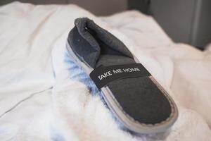 Slippers with take me home text on bed of hotel photo