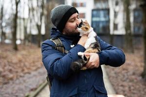 Man hold kitten in hands outdoor at park. photo