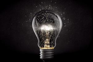 Sparkling light bulb on black background with ample copy space photo
