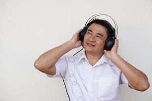 Happy Asian man listens to music from headphone. Concept, relax time with music and songs. photo