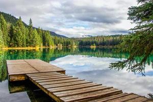 Dock in a calm lake surrounded by pine trees at Valley of the Five Lakes, Jasper National Park, Alberta, Canada photo