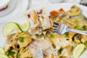 Pieces of Pomfret fish on a fork close-up. photo