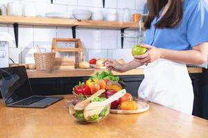 Diet, white-skinned young Asian woman in a blue shirt eating vegetable salad and apples as a healthy diet, opting for junk food. Female nutritionist losing weight. healthy eating concept. photo