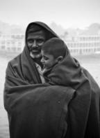 Bangladesh enero 06, 2014 un chico y su padre acecho el invierno río con el lleno cuerpo de vistiendo un grueso cobija en un invierno Mañana. foto