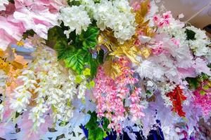 Colorful artificial paper flowers hanging on a stage. wedding decoration. Plastic colorful decorated flower. photo