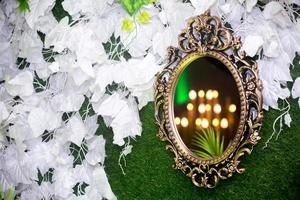 Green artificial grass based wedding stage with handcrafted oval-shaped vanity wall mirror decoration background. Plastic artificial flower. Wedding decoration. photo