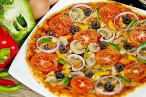 Popular colorful ingredients as like tomatoes, cheese, mushroom, capsicum, olives and other ingredients baked healthy Pizza. photo