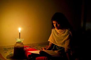 A young girl studying at home with candlelight after electricity load shedding at Dhaka City. photo