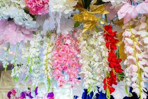 Colorful artificial paper flowers hanging on a stage. wedding decoration. Plastic colorful decorated flower. photo