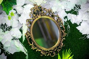 Green artificial grass based wedding stage with handcrafted oval-shaped vanity wall mirror decoration background. Plastic artificial flower. Wedding decoration. photo