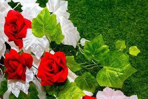 Red, green, and white flower background. Plastic artificial flower. Plastic colorful decorative leaves. photo