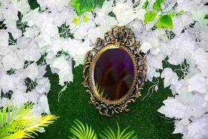 Green artificial grass based wedding stage with handcrafted oval-shaped vanity wall mirror decoration background. Plastic artificial flower. Wedding decoration. photo