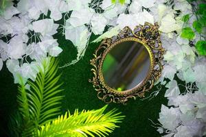 Green artificial grass based wedding stage with handcrafted oval-shaped vanity wall mirror decoration background. Plastic artificial flower. Wedding decoration. photo