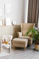 Modern Scandinavian living room interior in beige colors. Armchair, palm tree in a pot, mockup frames on the wall photo