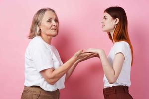 grandmother and granddaughter are standing side by side family friendship fun pink background photo