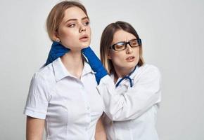 A nurse in blue gloves examines a patient in a white T-shirt on a light background photo