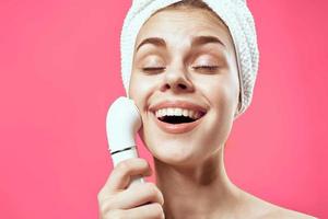 woman with bare shoulders with a towel on her head cleaning the skin photo