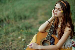 hippie eco simpático mujer con un guitarra relajante en naturaleza sentado en un tartán por el lago en el noche en el rayos de el ajuste Dom. un estilo de vida en armonía con el cuerpo y naturaleza foto