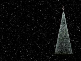 glowing snow and christmas tree decoration on black background photo