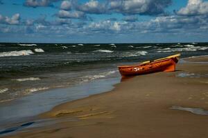 an orange lifeguard boat on a beach in leba in Poland on a warm  day photo