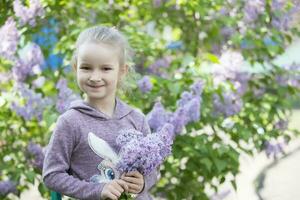 un niño en un lila. ordinario niña preescolar con un ramo de flores de primavera flores foto
