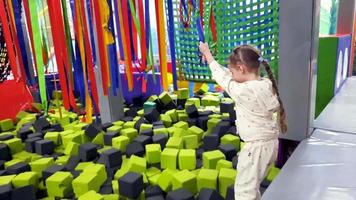 The girl swings among the soft cubes in the children's play center. Leisure of a happy child. Video. video