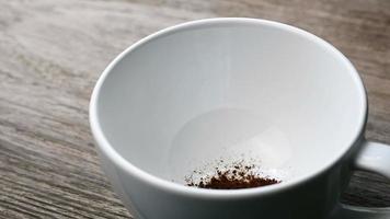 dichtbij omhoog van zetten ogenblik koffie in een kop Aan houten tafel en gieten heet water in de koffie. video