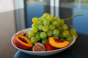 plates with healthy fruit, green grapes, peach, fig photo