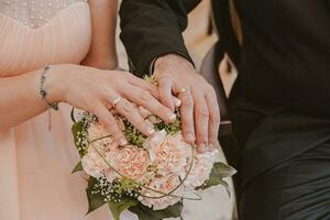 wedding bouquet with the hands of the bride and groom with wedding rings moments after the wedding photo