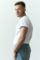 View from the back shot of handsome serious tanned man guy in basic t-shirt looks at camera posing on white background. Fashion Style New Collection Offer. Copy space for ad. Model snap photo