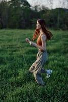 A young woman exercising outside and running in the park. in the evening on the green grass into the sunset photo