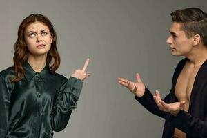 A woman shows her thumb up and a puzzled man gestures with his hands on a gray background photo