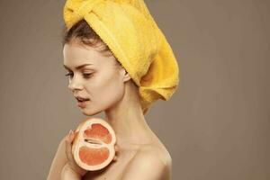 cheerful woman with yellow towel on her head grapefruit clear skin beige background photo