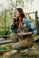 A woman with a smile takes care of the health of a chicken and holds a chicken in her hands while working on a farm in nature feeding the birds organic food photo