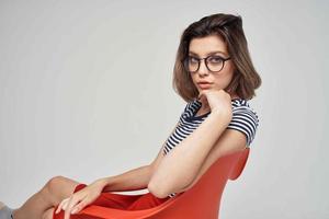 beautiful woman in a striped T-shirt sitting on the red chair modern style hairstyle photo