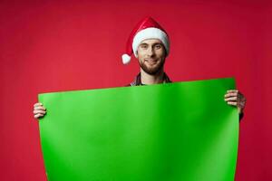 emotional man in a christmas hat with green mockup red background photo